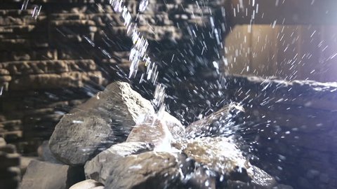 Water flowing on the stone in sauna. Spa Still Life. wellness and spa concept, sauna interior. Slow motion