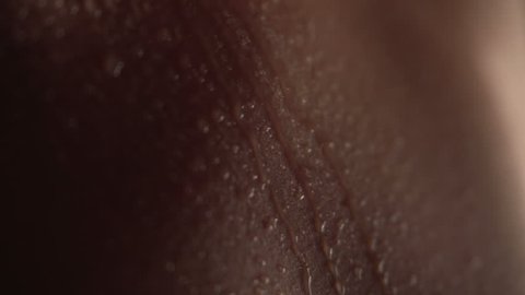 Texture of the skin close-up. Drops of water roll down the body. Young beautiful girl body. Macro