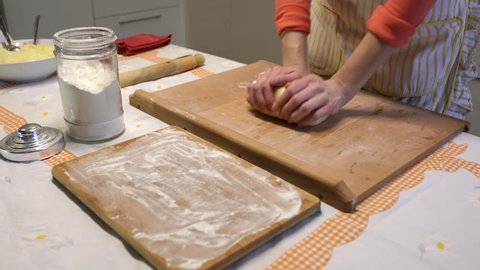 Woman knead the dough and cutting it into slices. Preparation of dumplings, traditional Ukrainian cuisine.