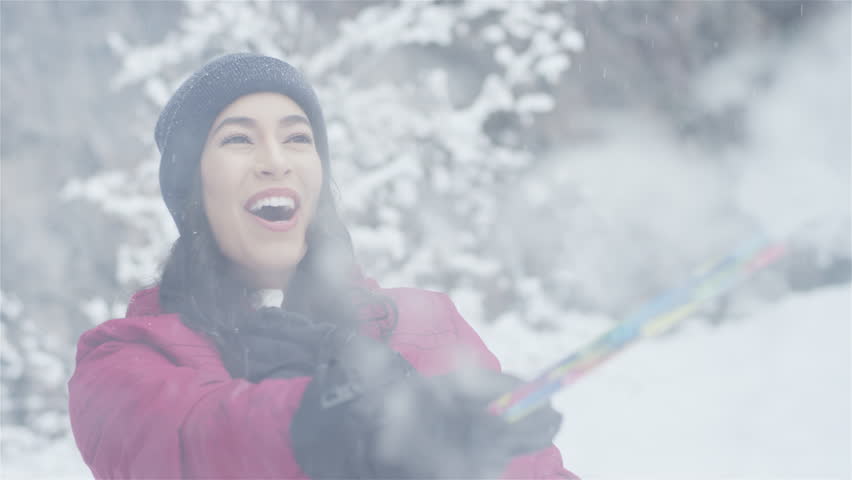 Beautiful young lady playing with a roman candle on a snowy day