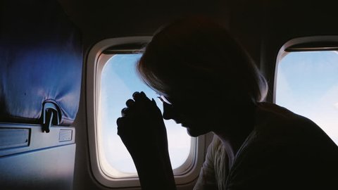 Anxiety and experience in flight. Silhouette of a young woman in an airplane, afraid to fly