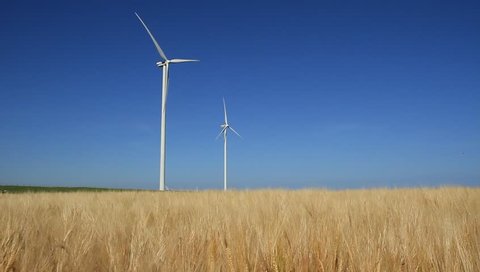 Two modern wind turbines generating sustainable energy in a field with wheat.