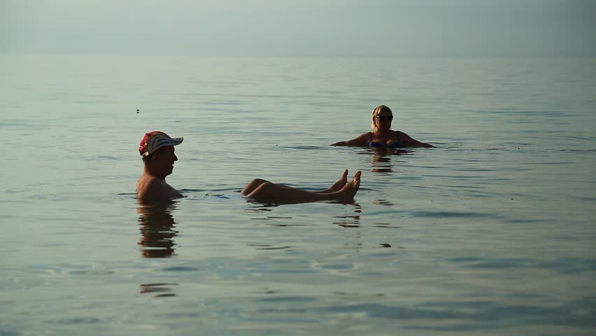 JORDAN, DEAD SEA, DECEMBER 8, 2016: People relax in very salty water of Dead Sea, Hashemite Kingdom of Jordan. People swim in Dead Sea