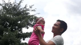 Video footage of happy father lifting her baby and kissing her head, shot outdoors