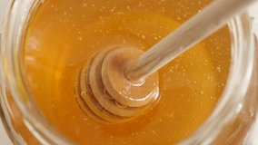 Golden sweet food substance and useful utensil 4K 2160p 30fps UltraHD footage - Wooden honey dipper used in jar close-up 3840X2160 UHD video