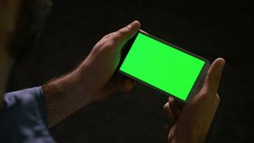 Man watching media content on smart phone with green screen