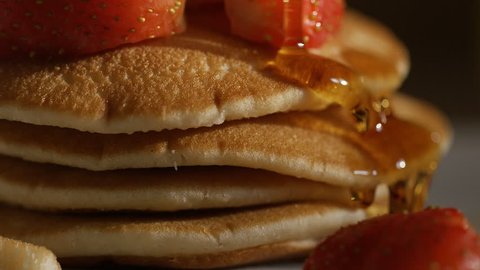 Maple syrup drizzled over stacked pancakes and strawberries