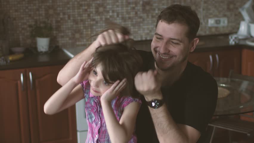 Making daddy. Dad makes funny Hairstyles to a little daughter. Family is having fun.