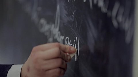 the hand writes on the blackboard a formula / the solution to the equation on the Board