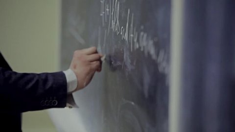 the hand writes on the blackboard a formula / the solution to the equation on the Board