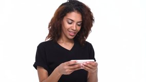 Happy young indian woman enjoys playing games on mobile phone isolated over white
