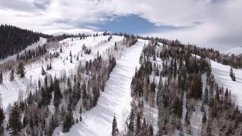 An aerial shot of people skiing in a beautiful mountain ski resort and riding up on the lifts