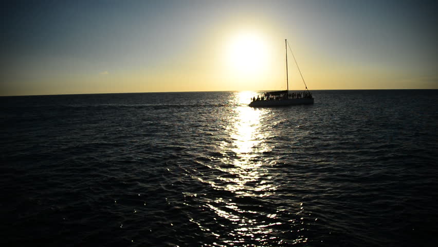Sailboat sails on Jamaican waters, sunset