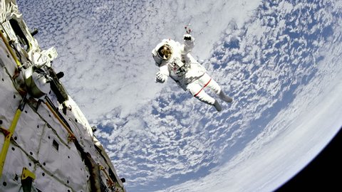 Astronaut are flying near the space station in outer space against the Earth background. Elements of this image furnished by NASA.