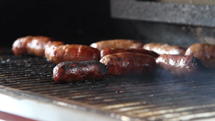 Sausage cooking slowly on the bbq outdoors