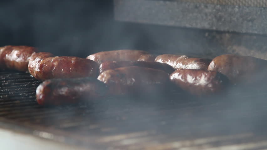 Sausage cooking slowly on the bbq outdoors