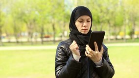 Muslim woman with a tablet in her hands outdoors.Full hd video