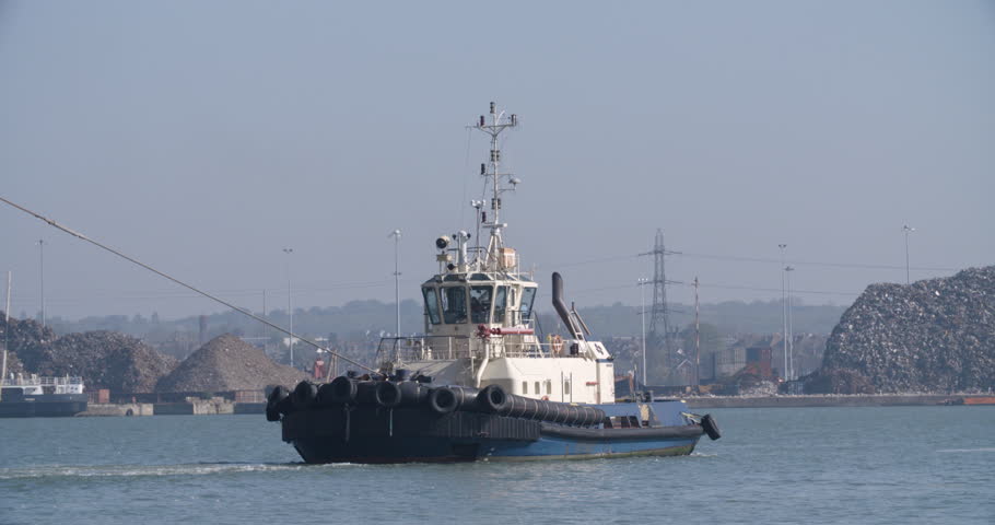 A tug boat pulls a container ship through Southampton Docks