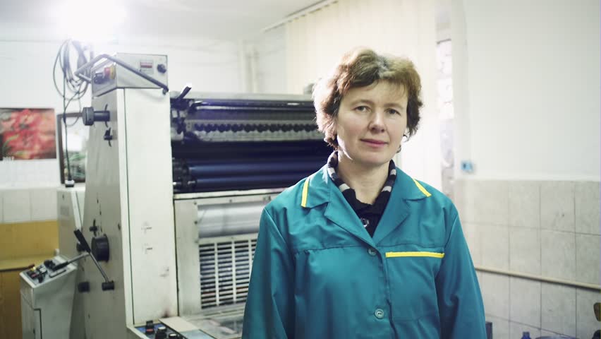 Worker in printing house. People working on printing machine in print factory.