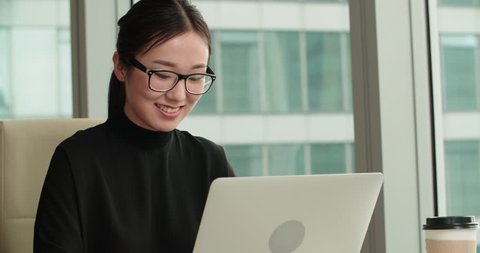 closeup of a young successful Asian business girl in a modern office, working using laptop