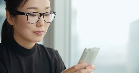 young business Asian girl texting on smartphone in office, close-up