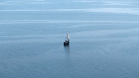 One-masted ancient sailboat floats in the sea or ocean, an old style ship on the water, aerial view