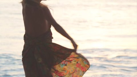 Happy pregnant woman dancing on a beach. Closeup. Sunset