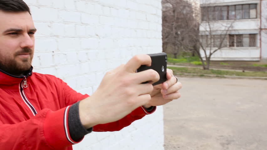 Young cute guy doing selfie near white brick wall