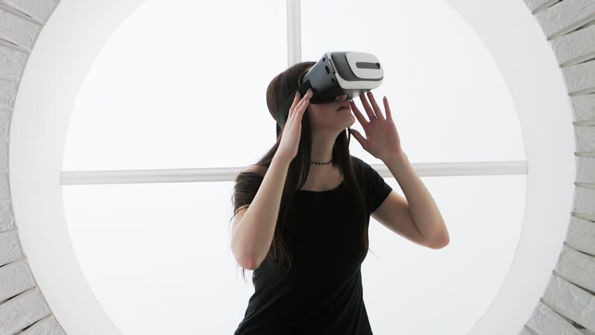 Woman in a virtual reality mask looks around. Virtual reality headset affords an immersive graphical experience. Royalty-Free Stock Footage #25852757