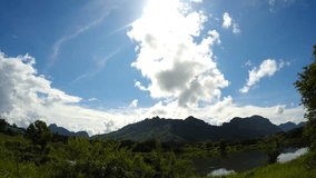 Timelapse of cloudy blue sky and strong sunlight above mountains and lake in Phangnga province, south of Thailand