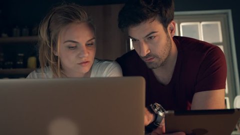 Couple using laptop in the kitchen at late night
