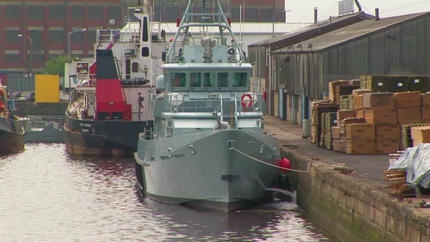 River work boats docked alongside warehouses and boxed goods in the port of Hull at Kingston upon Hull, UK
