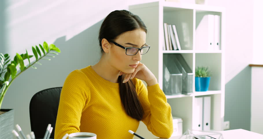 Young business woman finishing work, take off glasses and stretching hands at the office