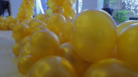 The design of a hall in the yellow balloons. Bunch of colored balloon decoration. Yellow background. Steadicam shot.