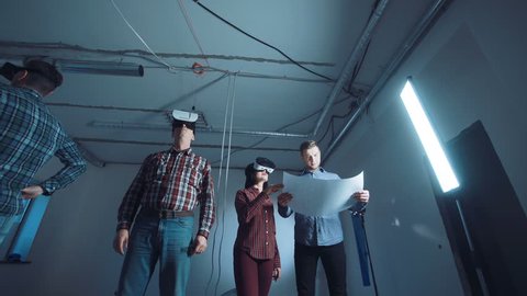 The people with blueprint and virtual reality headsets on a construction site.