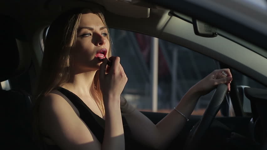 Beautiful Woman applying makeup in the car