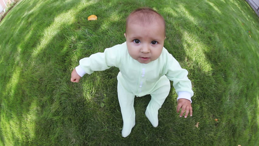 Adorable sitting toddler on lawn of garden, fisheye