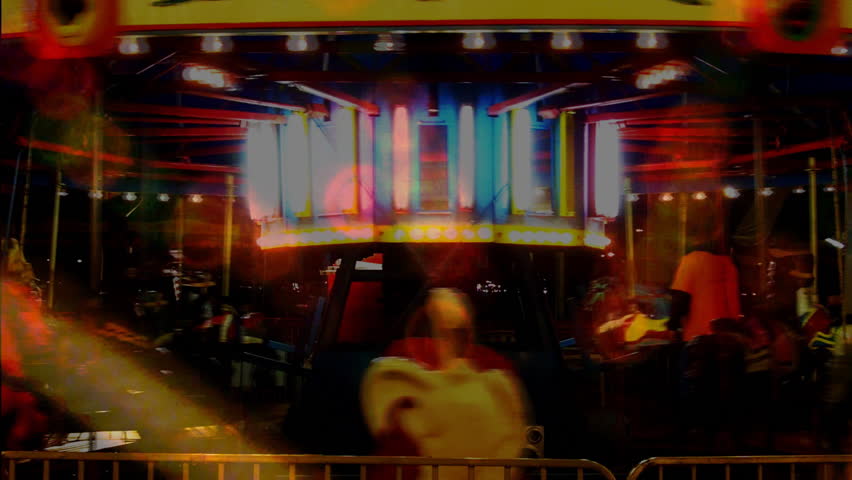 A glowing carousel at night combined with rotating and blinking amusement park