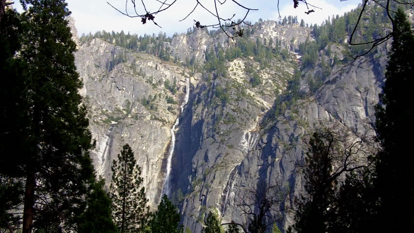 A scenic landscape of sheer granite cliff faces with a cascading waterfall