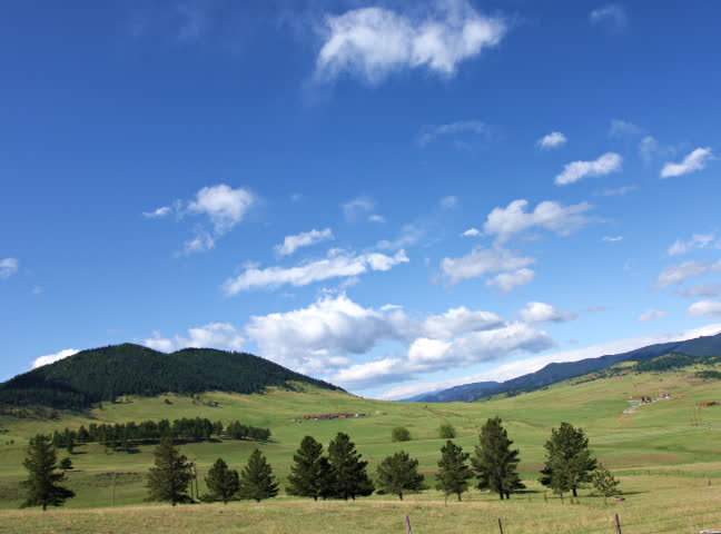 A wide-angle timelapse of a scenic mountain meadow, and then flying into the