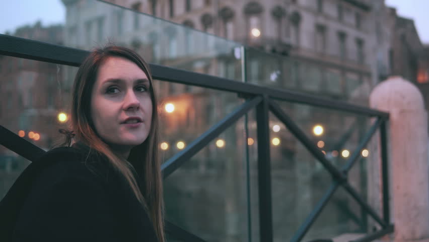 Young woman sitting outside, man comes and sits near her. Attractive couple eating sandwiches and talking.