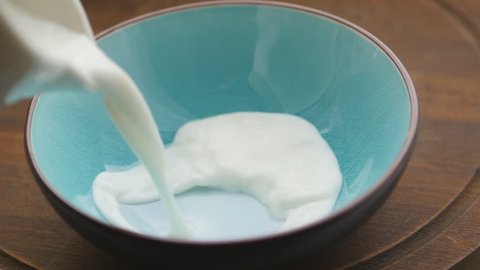 Pouring milk into a blue bowl. Slow motion