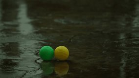picking up green and yellow balls ( kid toys ) in the rainy day 
