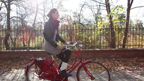 Young woman riding on bike in autumn setting.
 – Stockvideo