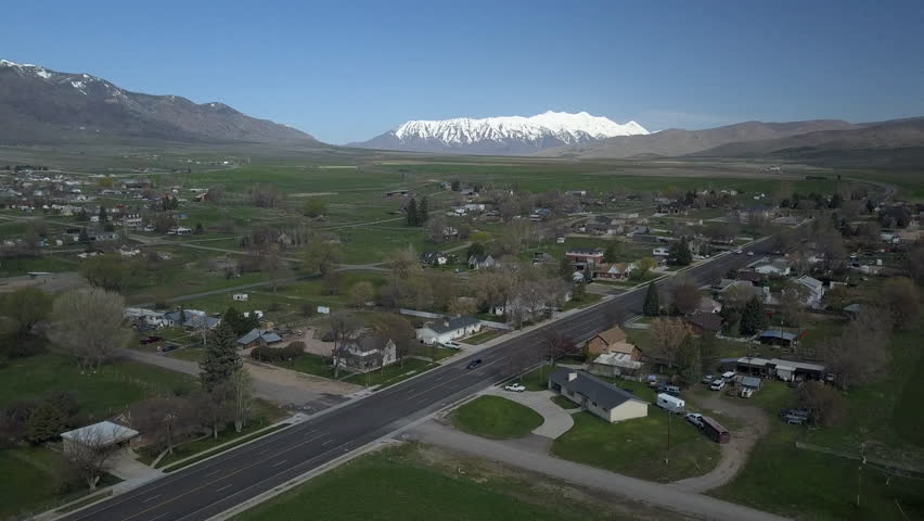 FOUNTAIN GREEN, UTAH - 15 APR 2017: Aerial rural farming town descend green. Spring time. Home, barns and agriculture field. Ranch agriculture way of life and income. Green fields and yards.