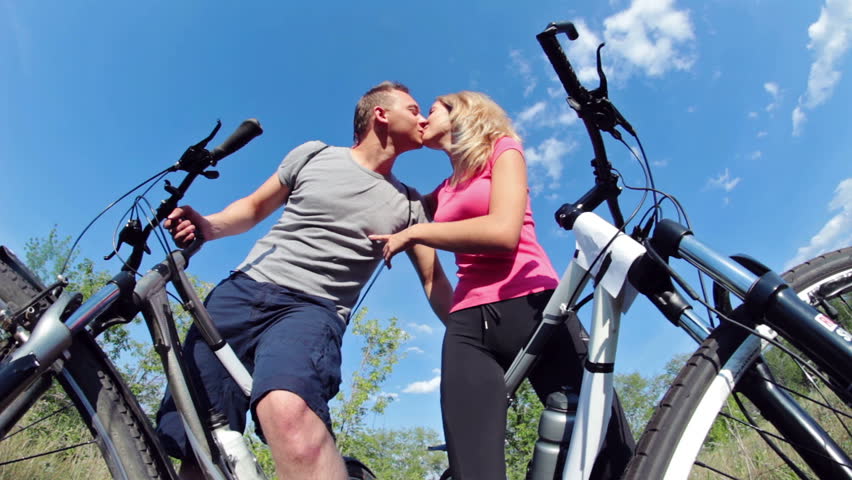 Two attractive couple holding their bikes and kissing 