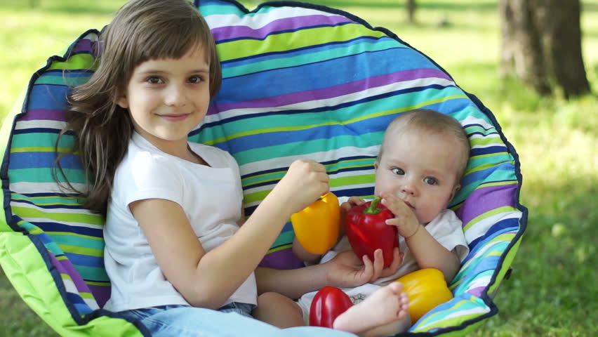 Sister and brother with vegetables in a chair
