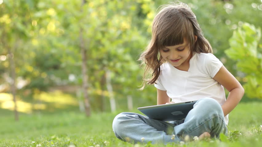 Girl with a Tablet PC sitting on the grass
