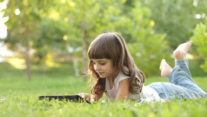 Girl with a tablet pc lying on the grass
