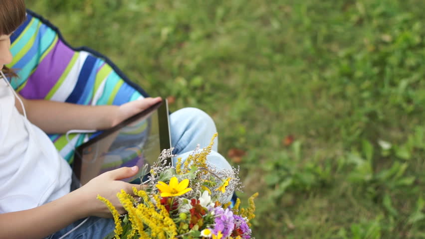 Girl with a Tablet PC and headphones playing outdoors
